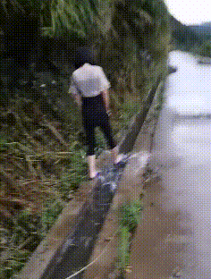无聊的妹子暴雨后在路边用脚趟水玩