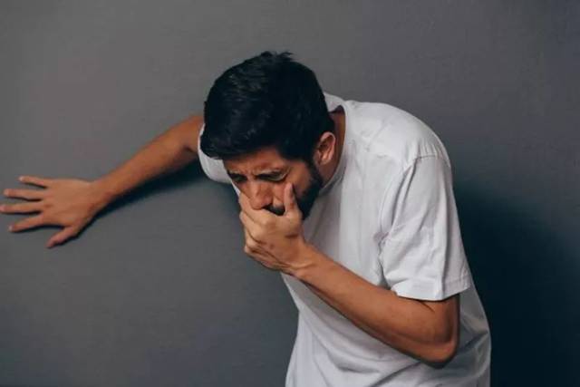 用手捂住自己嘴巴防止呕吐的男人