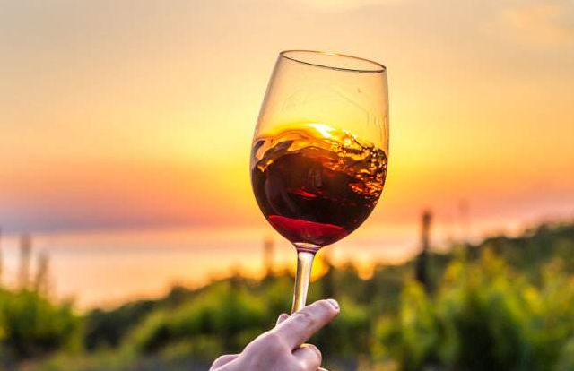 在夕阳下举起红酒杯品尝美酒