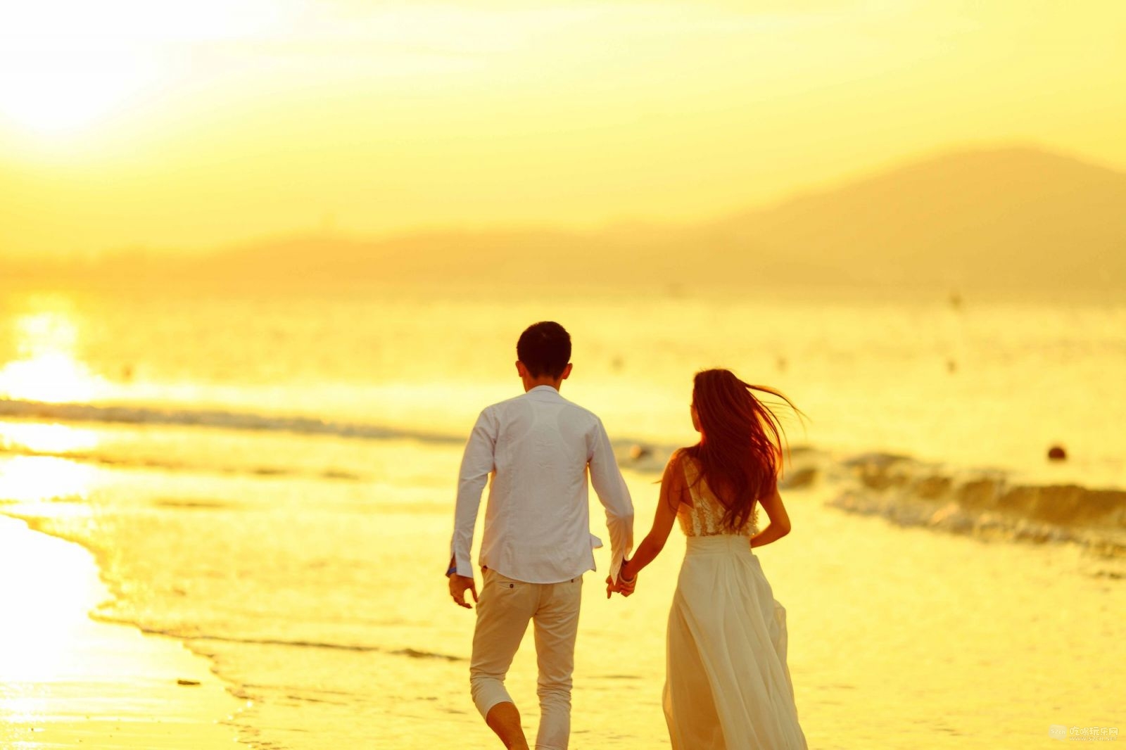 牵手在沙滩上散步的一对新人